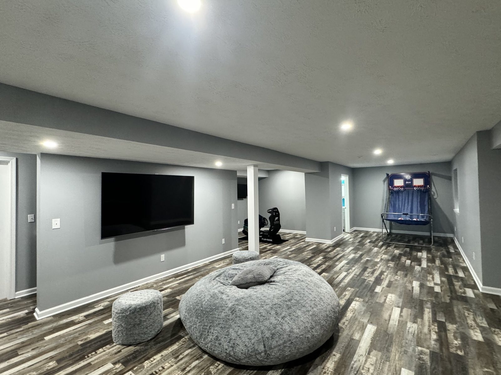 Finished basement lounge with a mounted television and wood look flooring