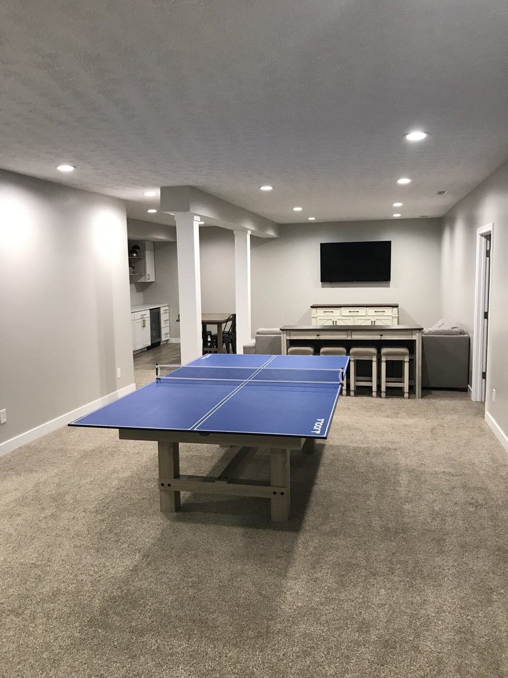 Finished basement with a ping pong table and lounge seating