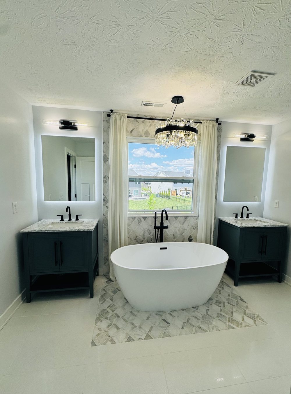 Freestanding soaking tub flanked by dark double vanities