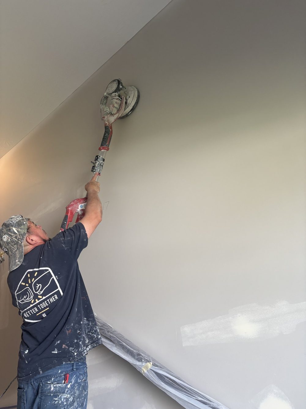 Painter cutting in a ceiling on a covered floor