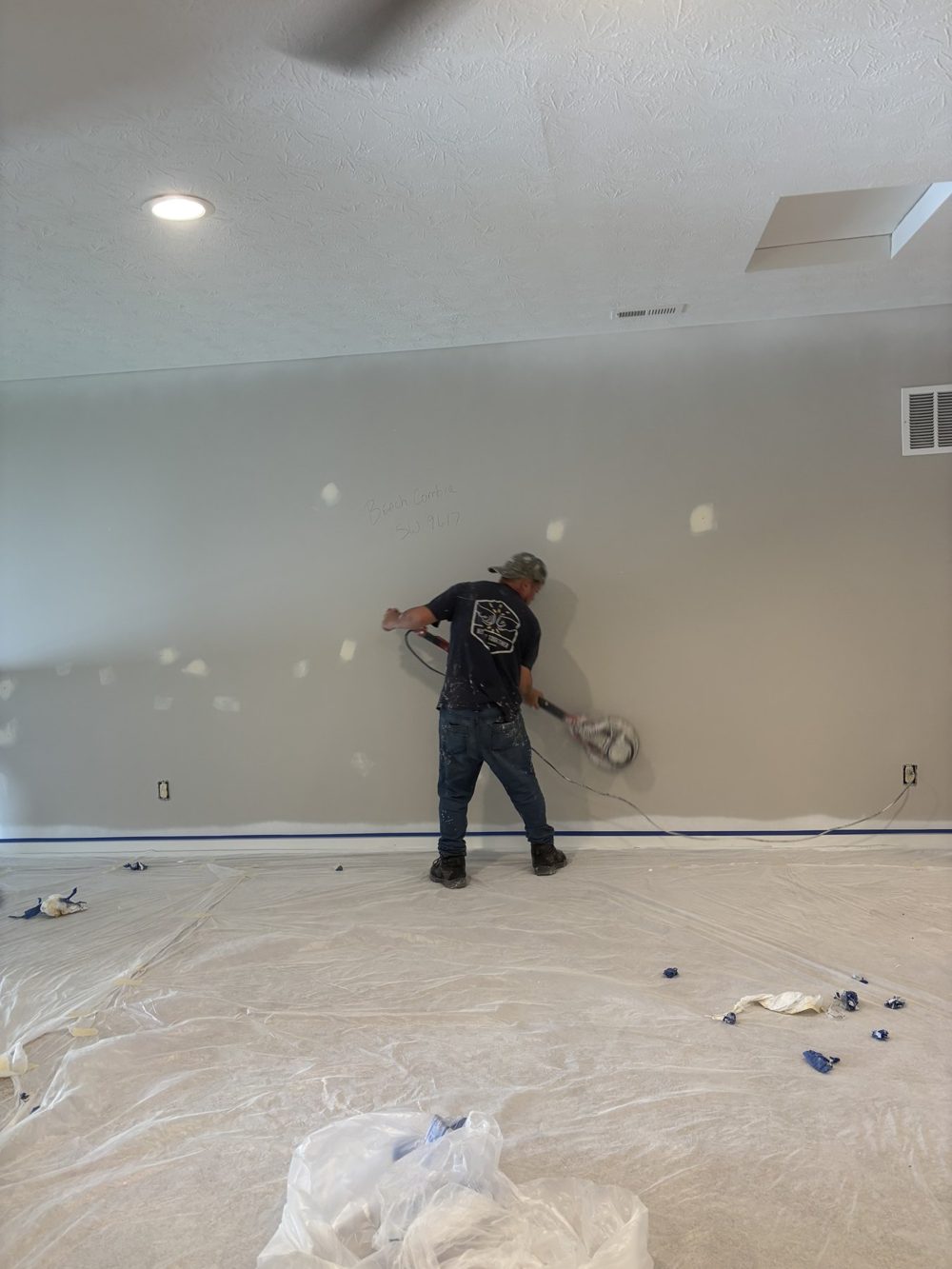 Painter working a wall in a masked and papered room