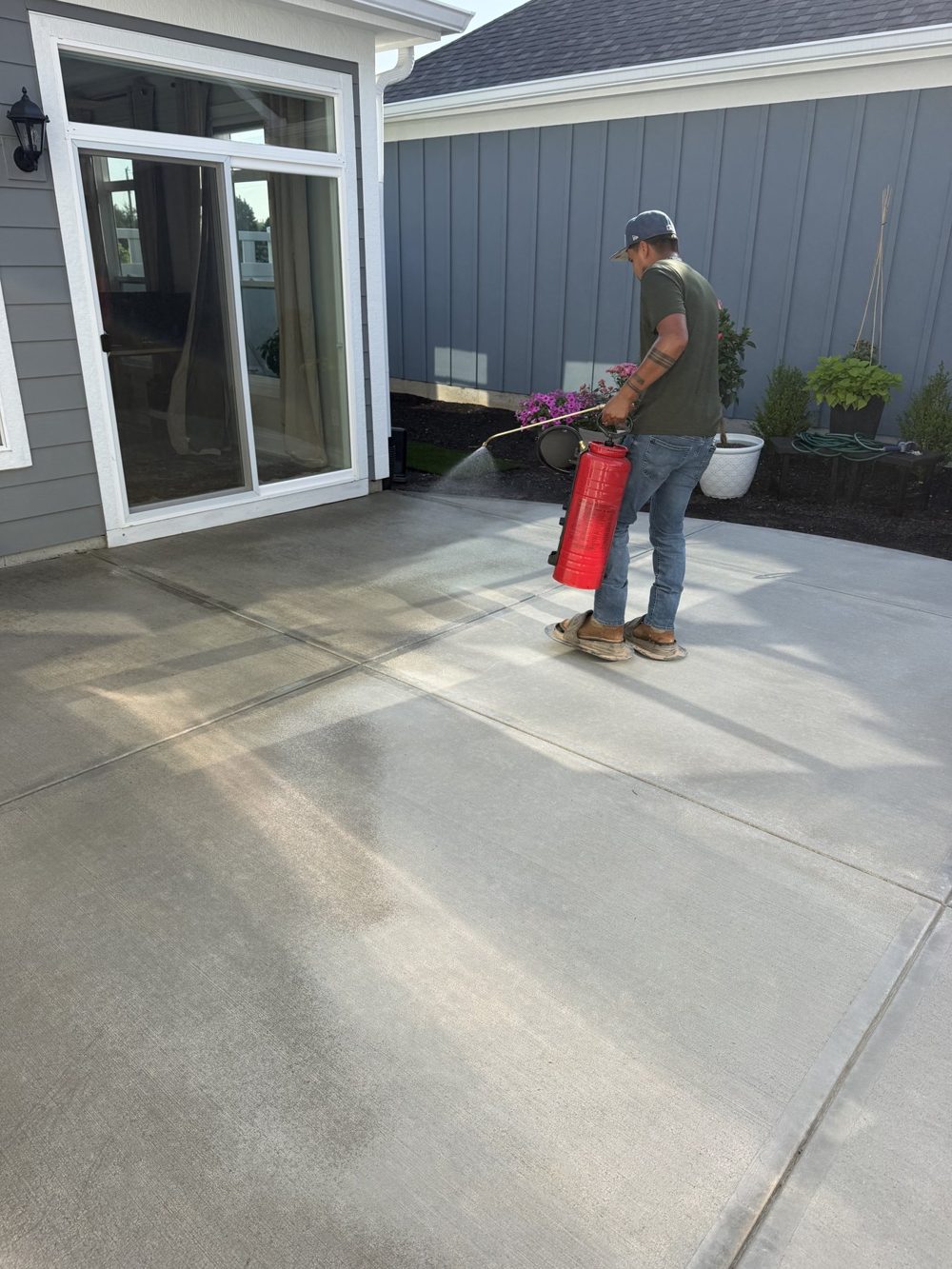 Crew member applying sealer to a concrete patio