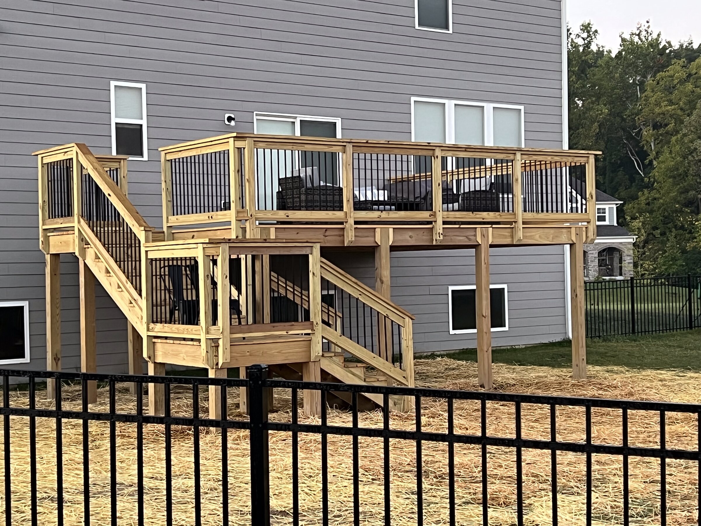 Two level wood deck with railings and stairs on the back of a home