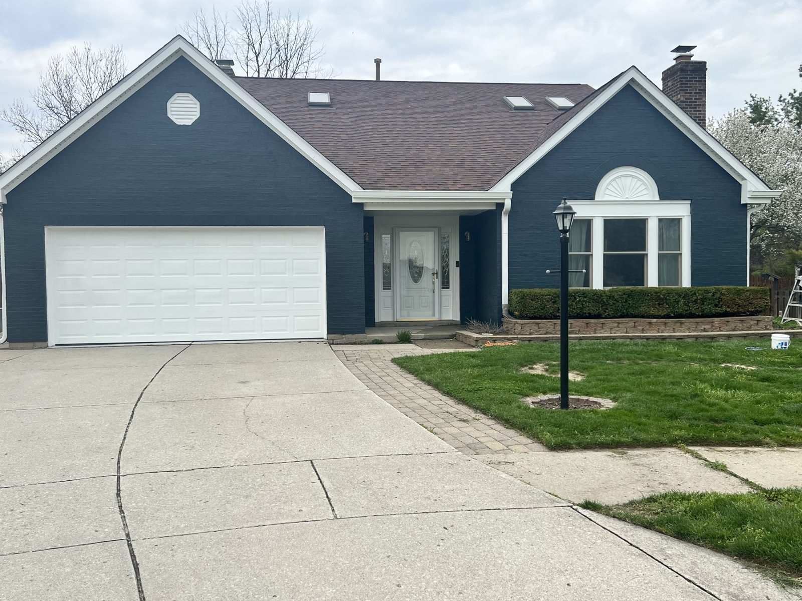 Blue painted home exterior with a white garage door and concrete drive