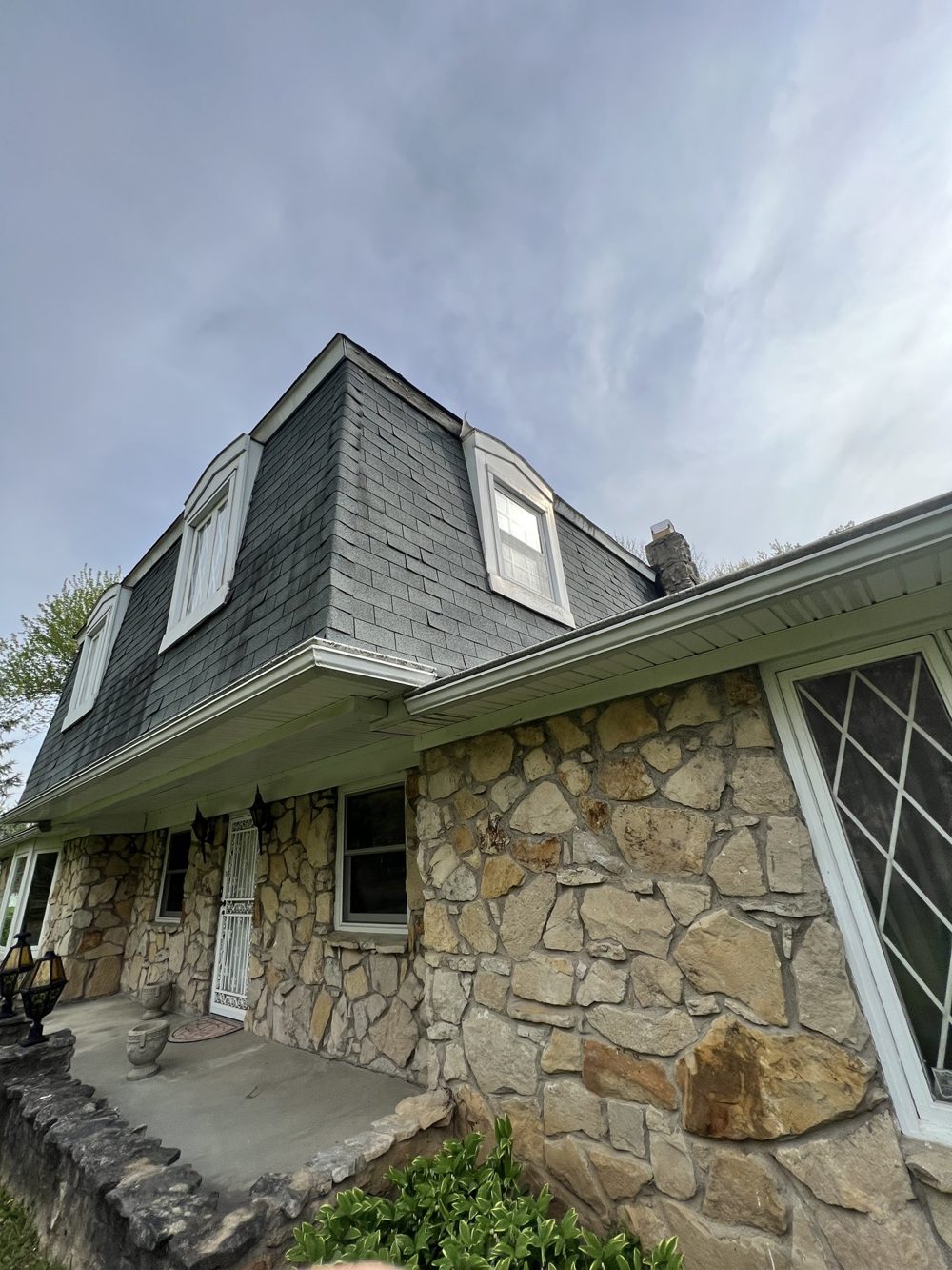 The same home before painting, with dated siding and stone