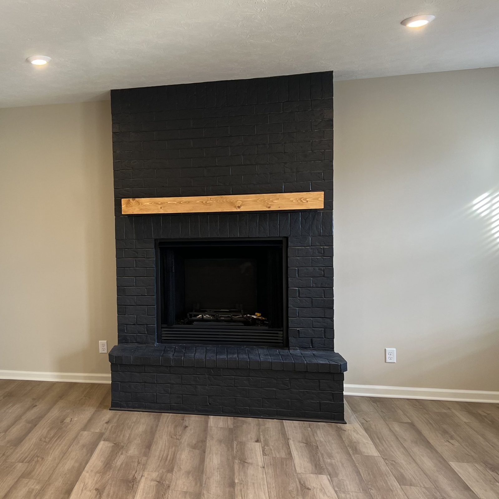 Painted black brick fireplace with a timber mantel