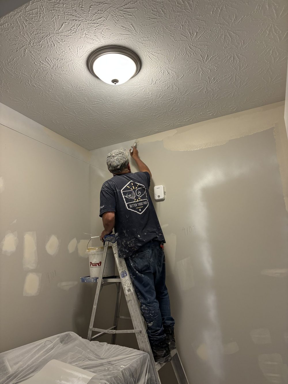 Painter on a ladder finishing a ceiling