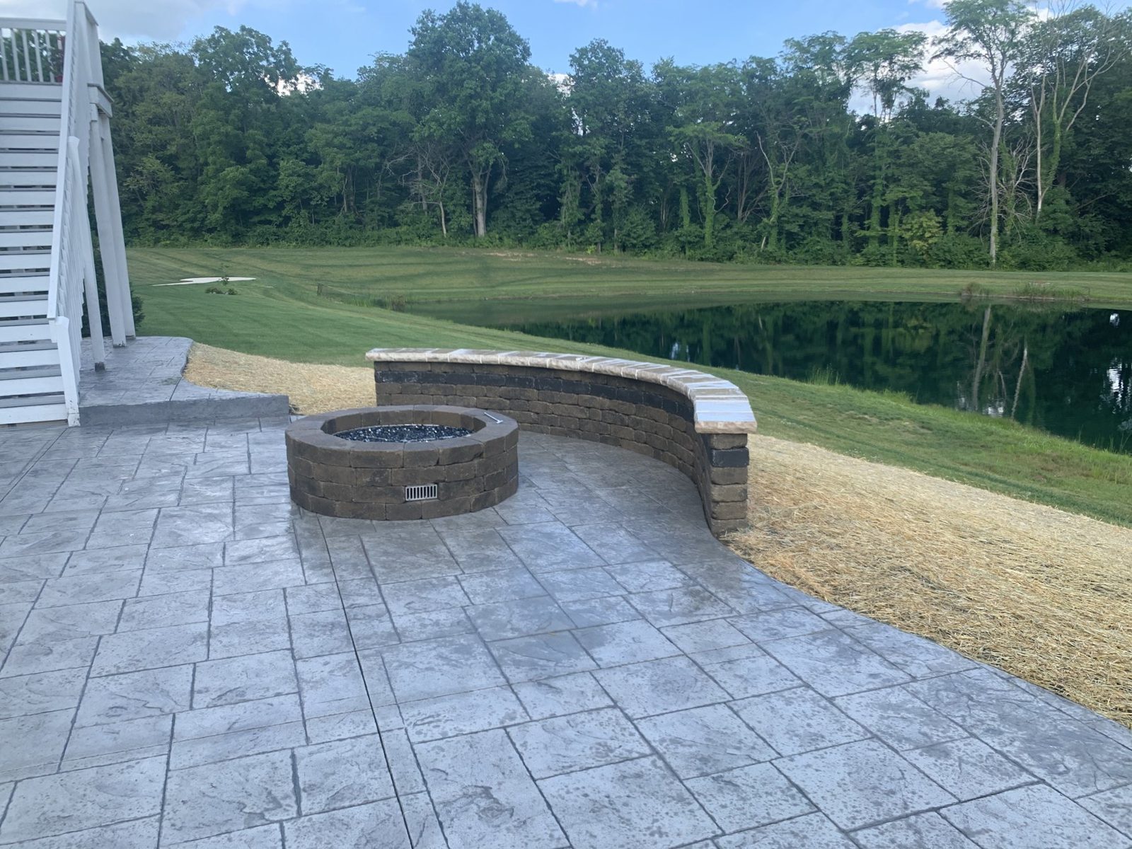 Curved stamped patio and sitting wall beside a pond