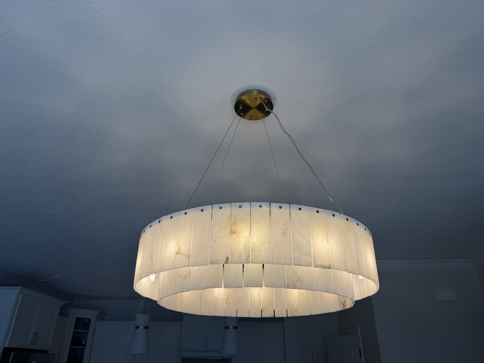 Large drum pendant light fixture installed on a painted vaulted ceiling