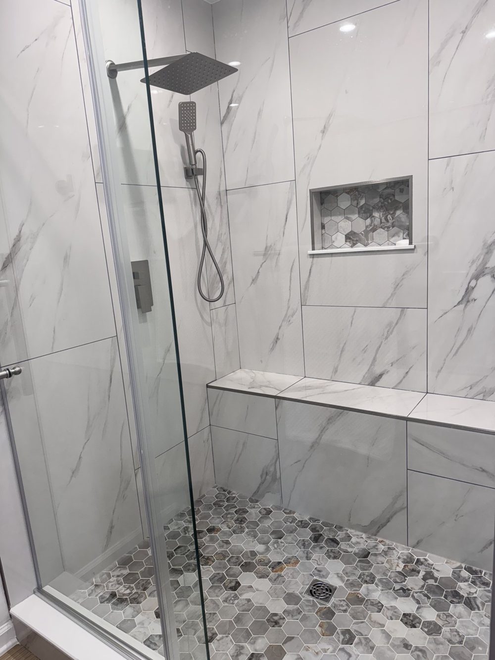 Marble tiled shower with a built in bench and rain head
