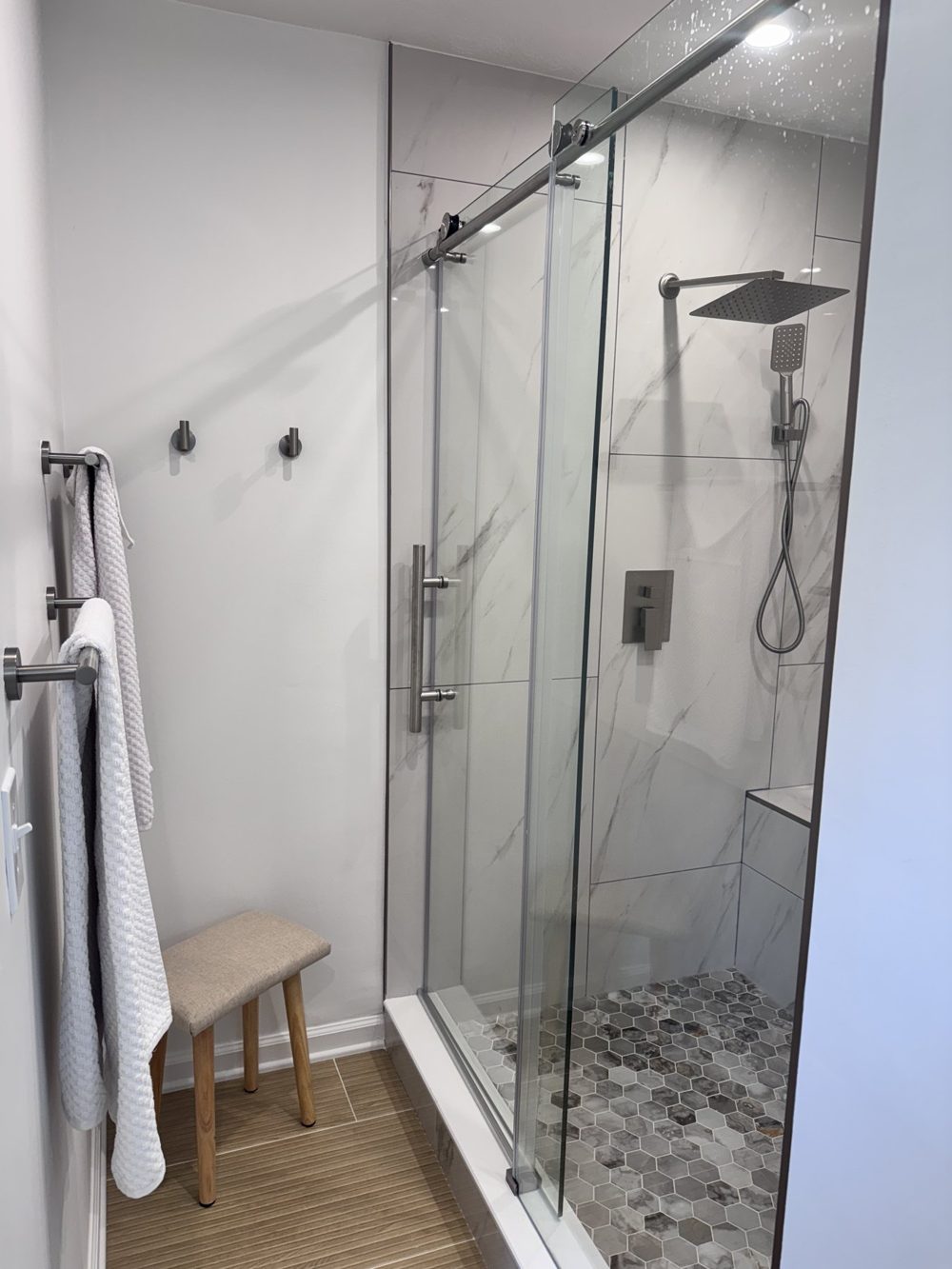 Frameless glass shower with marbled tile and a body jet panel