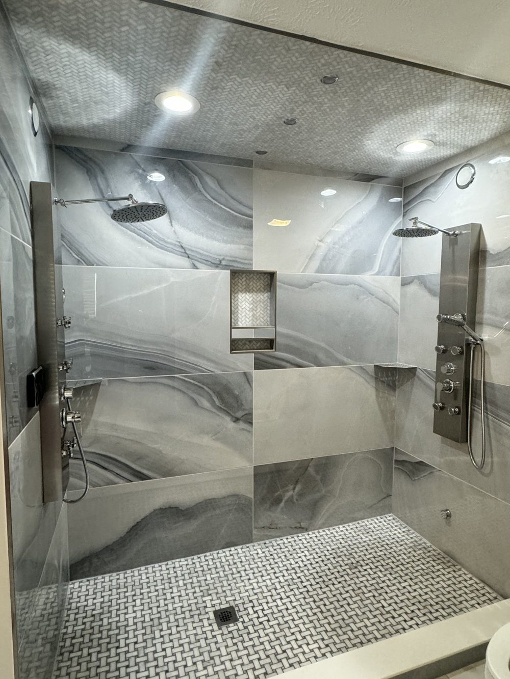 Walk in shower with marbled large format tile and a mosaic floor