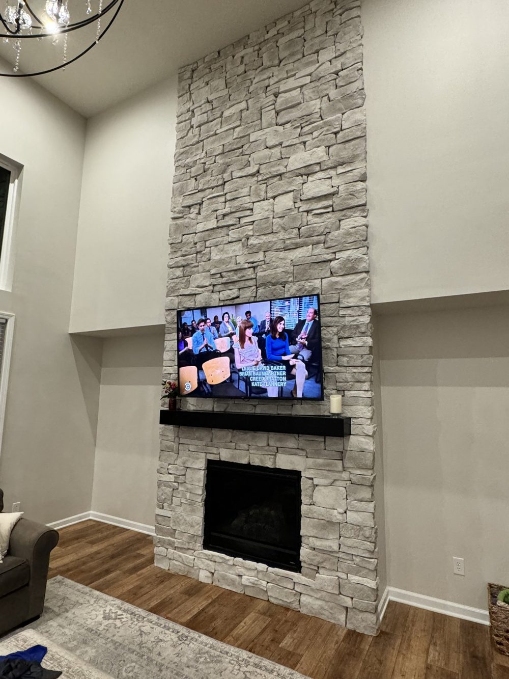 Television mounted above a stacked stone fireplace with built in shelving